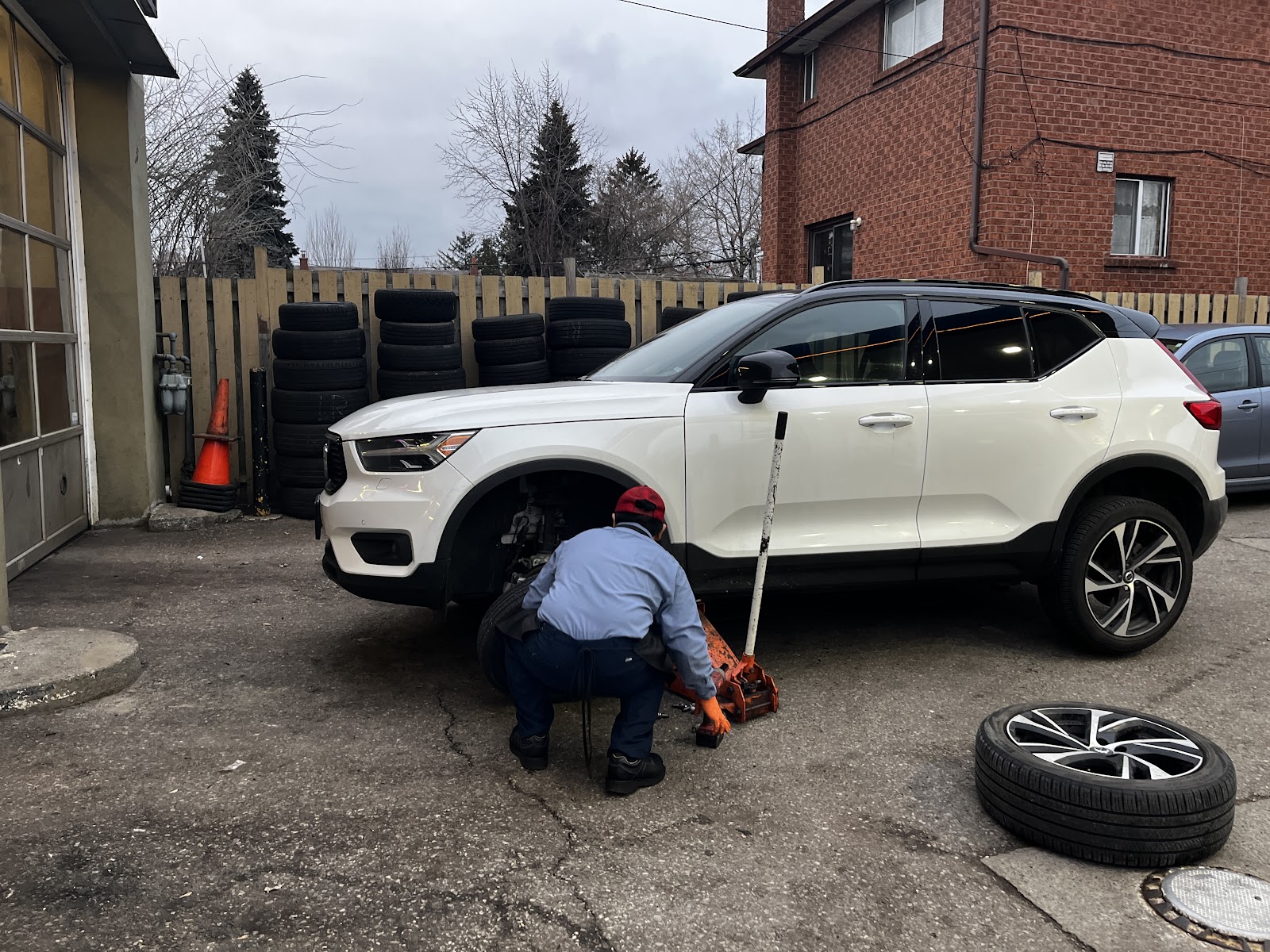 A mechanic at Edmar's Auto Service changing a wheel in the rear yard of the shop